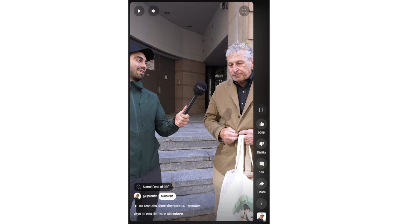 A vertical video frame shows a young man with dark hair holding a microphone and interviewing an older man with gray hair. The older man is holding a white tote bag. The video includes text overlays like "Search 'end of life'," "@Sprouht," "83 Year Olds Share Their BIGGEST Mistakes," and "What it Feels Like To Be Old #shorts." Video controls and metrics are visible on the right side, including view count (904K), likes, dislikes, comments (140), share, and save options.