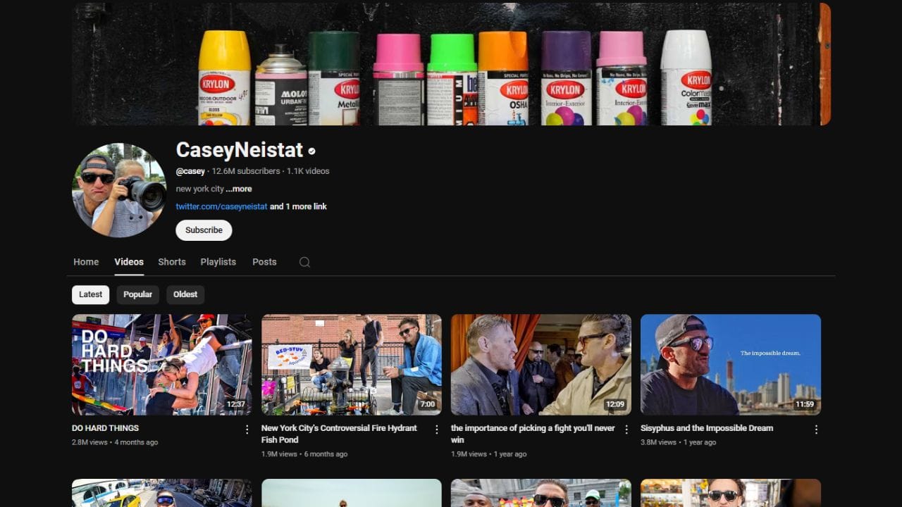 A YouTube channel page screenshot of "Casey Neistat" (@casey) with 12.6M subscribers. The channel banner shows a row of Krylon spray paint cans. The "Videos" tab displays four thumbnails with titles like "DO HARD THINGS," "New York City's Controversial Fire Hydrant Fish Pond," "the importance of picking a fight you'll never win," and "Sisyphus and the Impossible Dream." The thumbnails feature Casey Neistat and various scenes from his videos. The video durations range from 7:00 to 12:09. The view counts range from 1.9M to 3.8M. The uploads date from 4 months to 1 year ago. The words "DO HARD THINGS" are prominently displayed on one of the thumbnails. The channel also has a "Subscribe" button.
