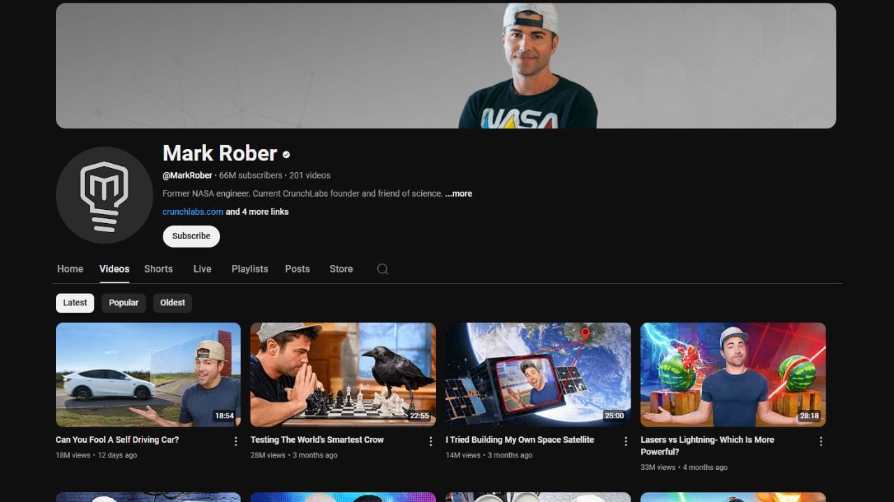 A dark-themed YouTube channel page for Mark Rober. The channel banner features Mark Rober wearing a NASA t-shirt and a baseball cap. The profile picture is a stylized "MR" logo. The channel name "Mark Rober" is in white letters, followed by a black dot. Below is the channel username "@MarkRober", the subscriber count (66 million), and the video count (201). The banner also includes the text "Former NASA engineer. Current CrunchLabs founder and friend of science ...more", a link to "crunchlabs.com", and a "Subscribe" button. The channel page displays tabs for "Home," "Videos," "Shorts," "Live," "Playlists," "Posts," "Store," and a search icon. Below these tabs are sorting options for "Latest," "Popular," and "Oldest." The video thumbnails show various science experiments and demonstrations, with titles like "Can You Fool A Self Driving Car?," "Testing The World's Smartest Crow," "I Tried Building My Own Space Satellite," and "Lasers vs Lightning- Which Is More Powerful?"