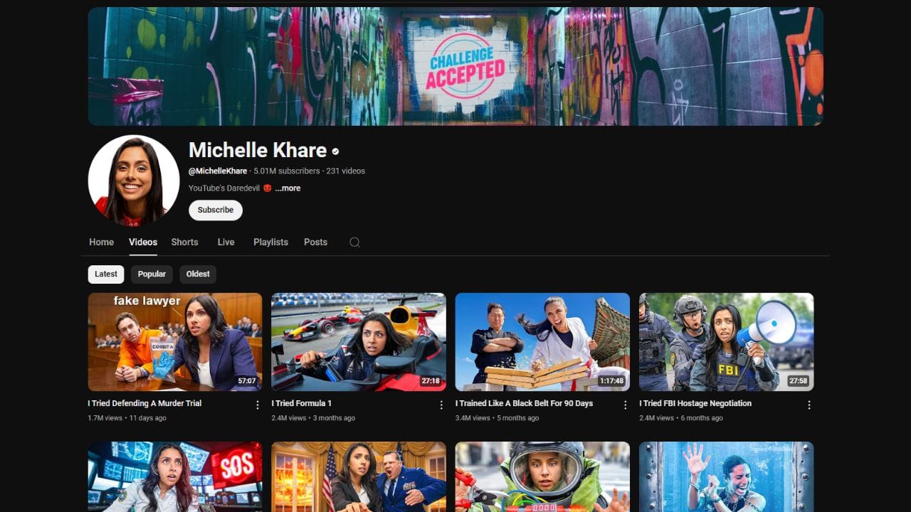 A dark-themed YouTube channel page for Michelle Khare. The channel banner features graffiti-style artwork with the text "CHALLENGE ACCEPTED." The profile picture shows Michelle Khare. The channel name "Michelle Khare" is in white letters, followed by a black dot. Below is the channel username "@MichelleKhare", the subscriber count (5.01 million), and the video count (231). The banner also includes the text "YouTube's Daredevil ...more" and a "Subscribe" button. The channel page displays tabs for "Home," "Videos," "Shorts," "Live," "Playlists," "Posts," and a search icon. Below these tabs are sorting options for "Latest," "Popular," and "Oldest." The video thumbnails show Michelle Khare participating in various challenges, with titles like "I Tried Defending A Murder Trial," "I Tried Formula 1," "I Trained Like A Black Belt For 90 Days," and "I Tried FBI Hostage Negotiation."